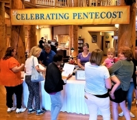 People at a registration table for Pentecost celebration