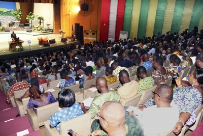 Person standing at lectern with large audience in Togo