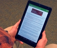 Person holding a tablet with a web article on it